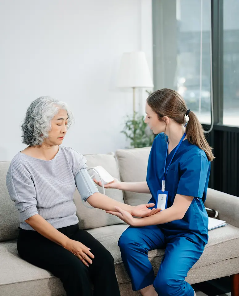 Nurse checking woman's blood pressure at home.