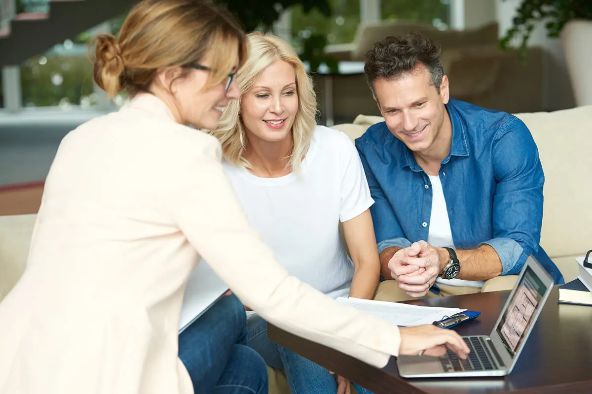 Three people looking at a laptop screen.